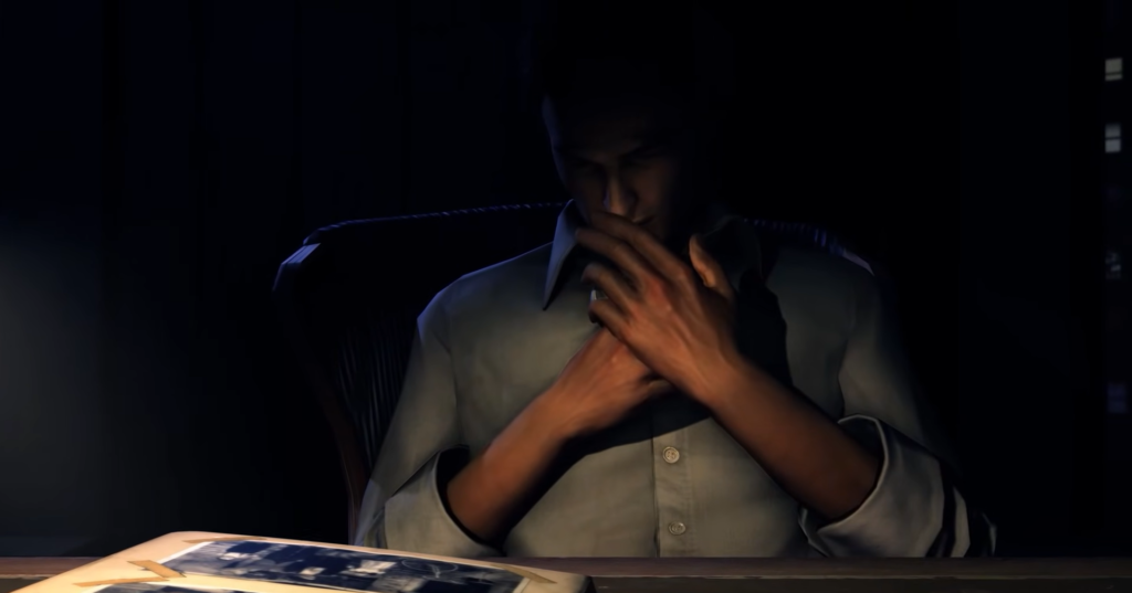 Мужчина сидит за столом, закрывает лицо руками