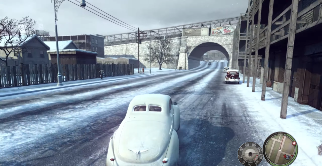 Белый автомобиль едет по заснеженной улице к арке