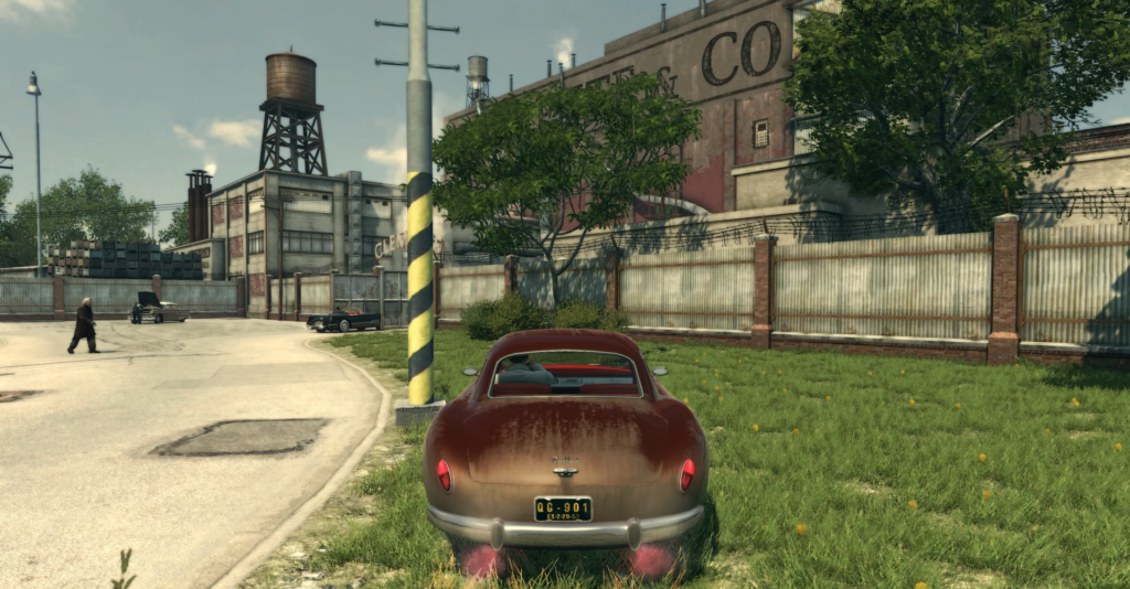 Красный автомобиль стоит у заводского забора и дороги