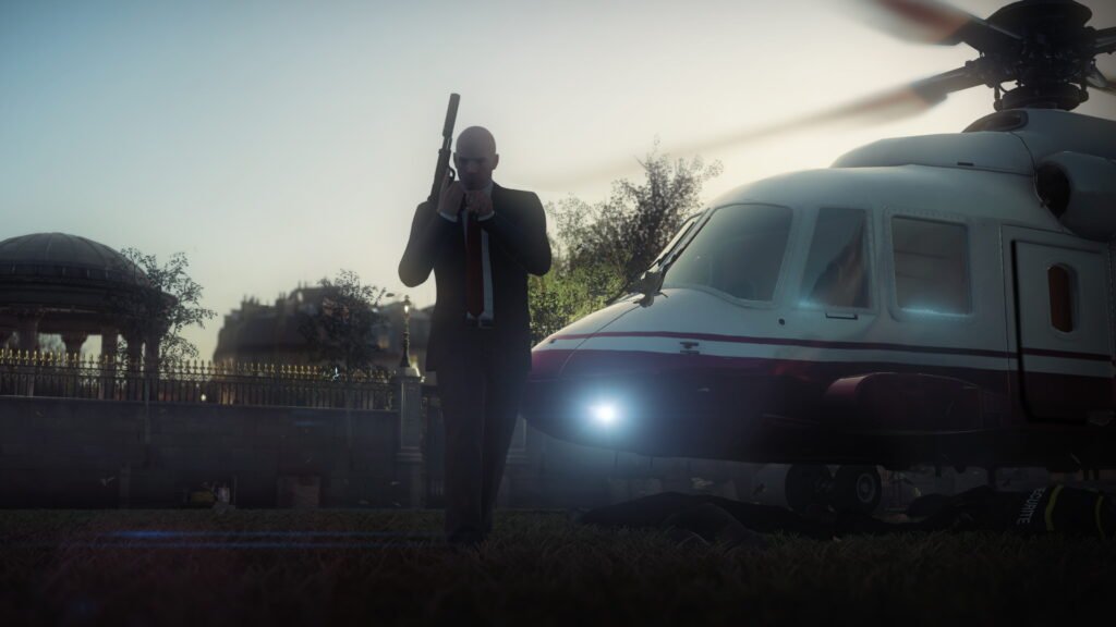 Агент 47 из Hitman стоит у вертолёта на лужайке